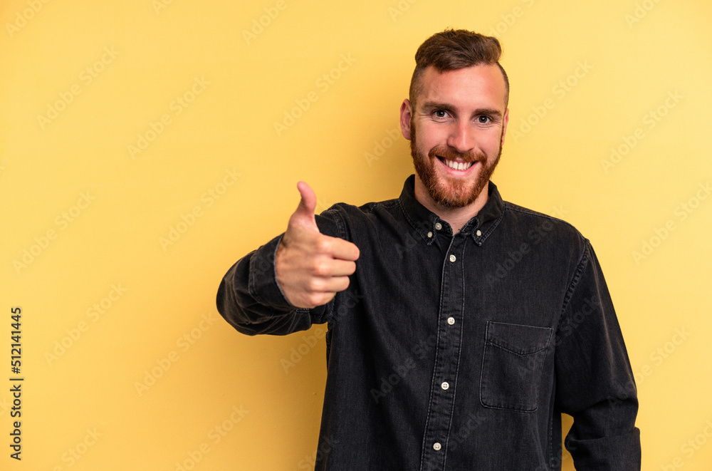 Young caucasian man isolated on yellow background smiling and raising thumb up Young caucasian man isolated on yellow background smiling and raising thumb up