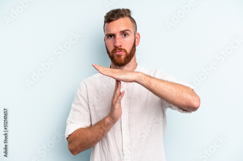 Young caucasian man isolated on blue background showing a timeout gesture.