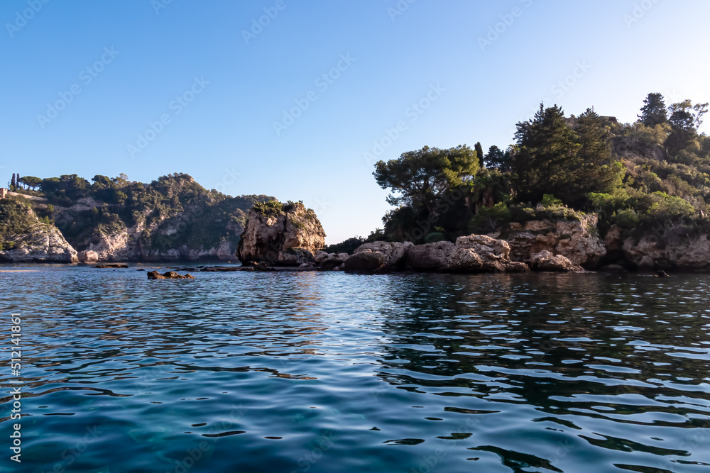 Touristic boat tour with panoramic view from open sea on the Mediterranean coastline near Isola Bella in Taormina, Sicily, Italy, Europe, EU. Coastal rock formations at Ionian Mediterranean sea