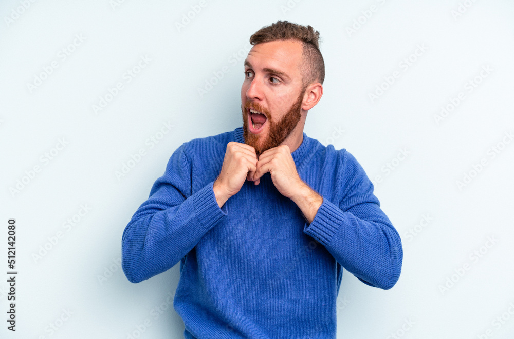 Young caucasian man isolated on blue background praying for luck, amazed and opening mouth looking to front. Young caucasian man isolated on blue background praying for luck, amazed and opening mouth looking to front.