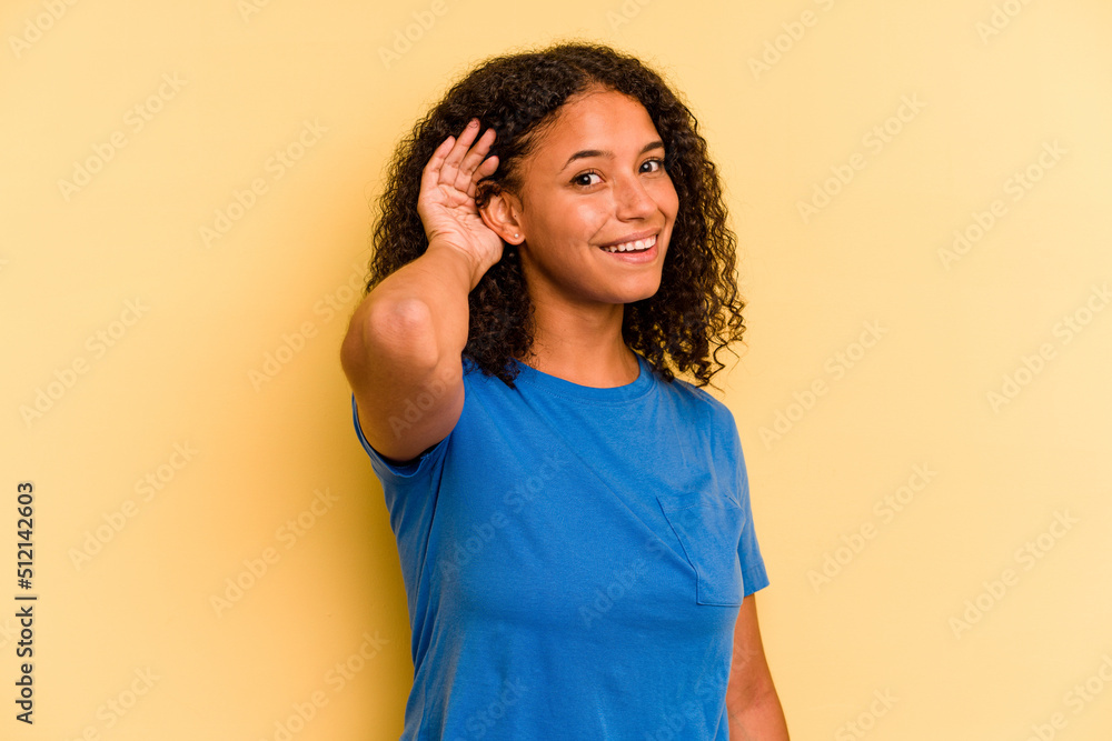 Young Brazilian woman isolated on yellow background trying to listening a gossip. Young Brazilian woman isolated on yellow background trying to listening a gossip.