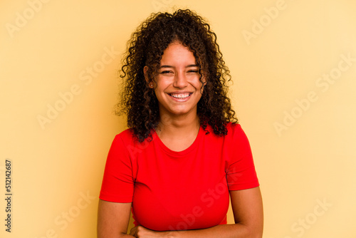 Young Brazilian woman isolated on yellow background laughing and having fun. © Asier
