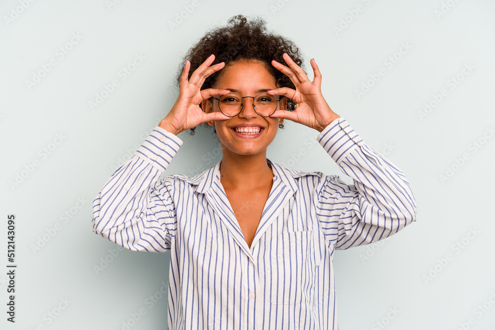 Young Brazilian woman isolated on blue background showing okay sign over eyes Young Brazilian woman isolated on blue background showing okay sign over eyes
