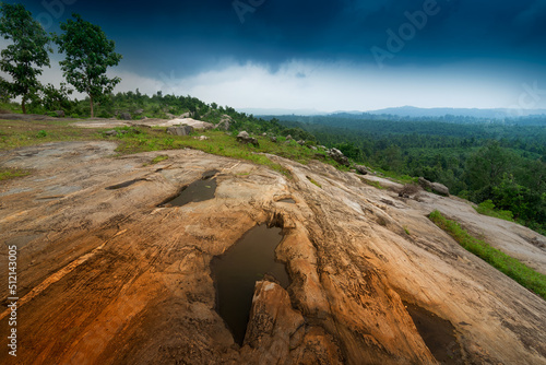 Mayur Paharh is a small hill of Purulia.  West Bengal  India. The beautiful rocks stored rain water below   with blue stormy clouds in the background signalling rain is approaching. Monsoon season.