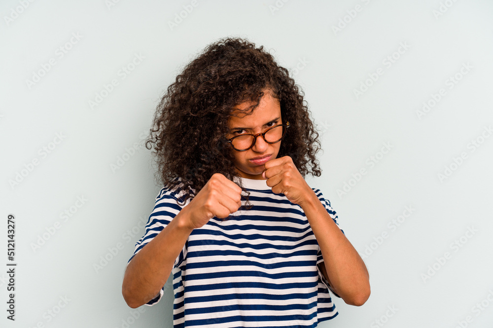Young Brazilian woman isolated on blue background throwing a punch, anger, fighting due to an argument, boxing. Young Brazilian woman isolated on blue background throwing a punch, anger, fighting due to an argument, boxing.