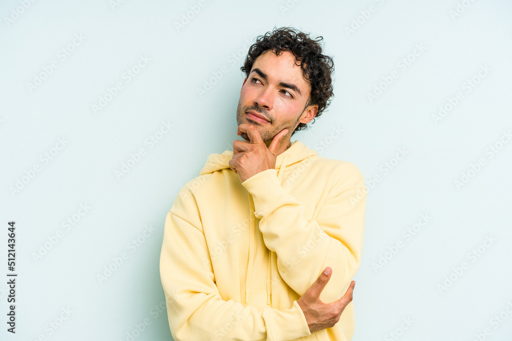 Fototapeta premium Young caucasian man isolated on blue background thinking and looking up, being reflective, contemplating, having a fantasy.
