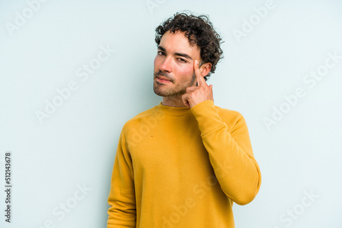 Young caucasian man isolated on blue background pointing temple with finger, thinking, focused on a task.