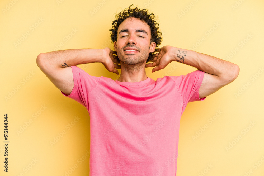 Young caucasian man isolated on yellow background feeling confident, with hands behind the head. Young caucasian man isolated on yellow background feeling confident, with hands behind the head.