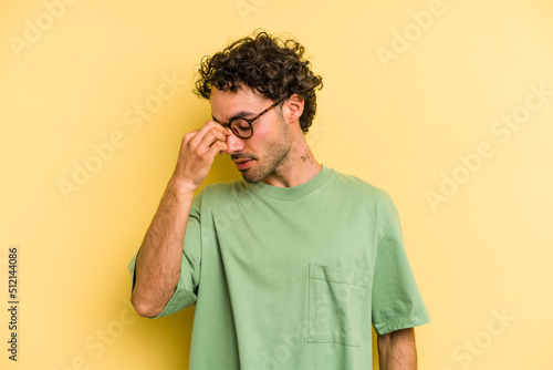 Young caucasian man isolated on yellow background having a head ache  touching front of the face.