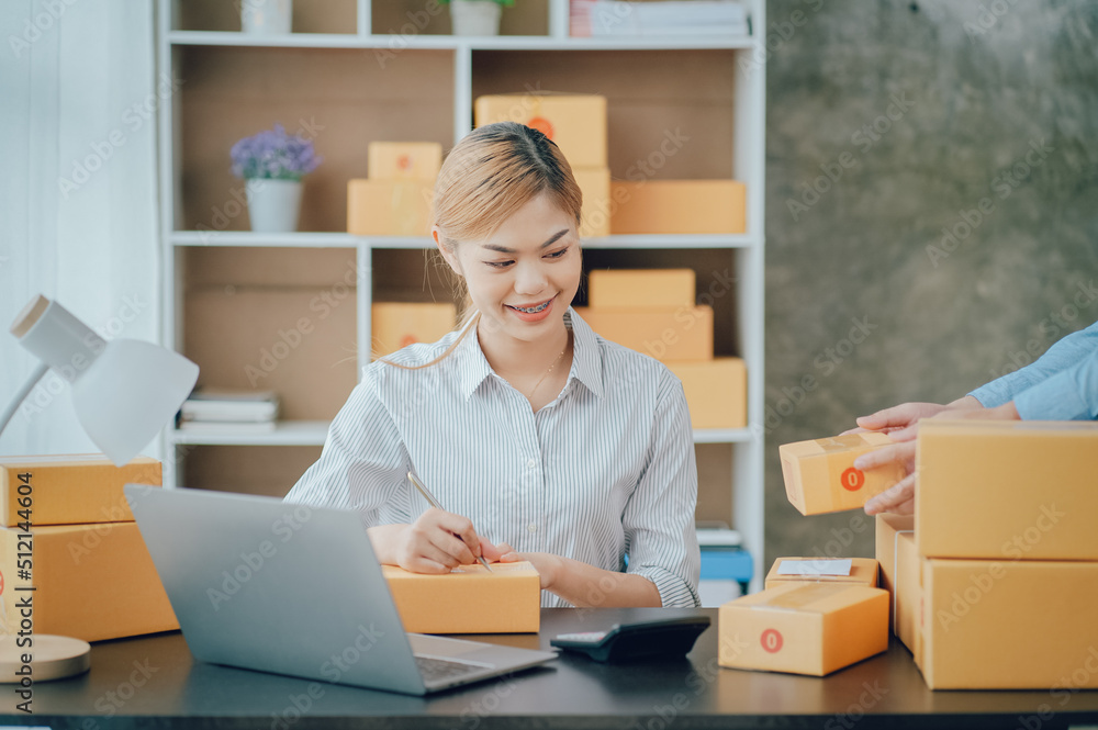 Looking camera, Startup small business SME, Entrepreneur owner using tablet taking receive and checking online purchase shopping order to preparing pack product box Looking camera, Startup small business SME, Entrepreneur owner using tablet taking receive and checking online purchase shopping order to preparing pack product box