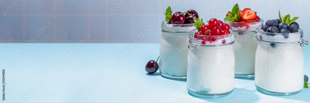 Variety of yogurts in portion glass jars. Healthy summer breakfast concept, with seasonal berry – strawberry, cherry, blueberry, currant Variety of yogurts in portion glass jars. Healthy summer breakfast concept, with seasonal berry – strawberry, cherry, blueberry, currant