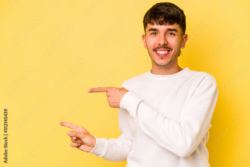 Young caucasian man isolated on yellow background excited pointing with forefingers away. Young caucasian man isolated on yellow background excited pointing with forefingers away.