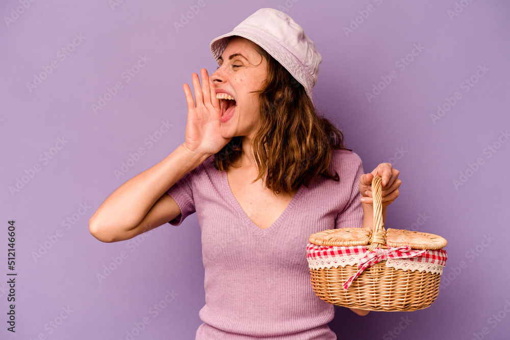 Young caucasian woman going on a picnic isolated on purple background shouting and holding palm near opened mouth. Young caucasian woman going on a picnic isolated on purple background shouting and holding palm near opened mouth.