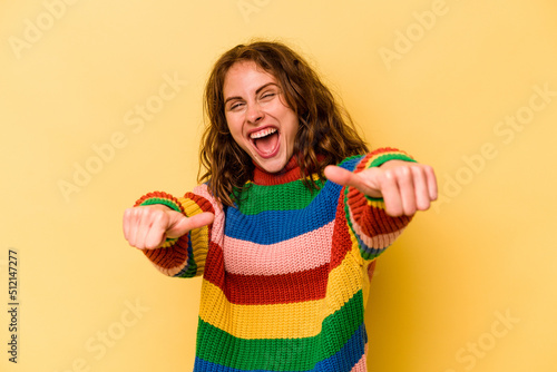 Young caucasian woman isolated on yellow background raising both thumbs up, smiling and confident.