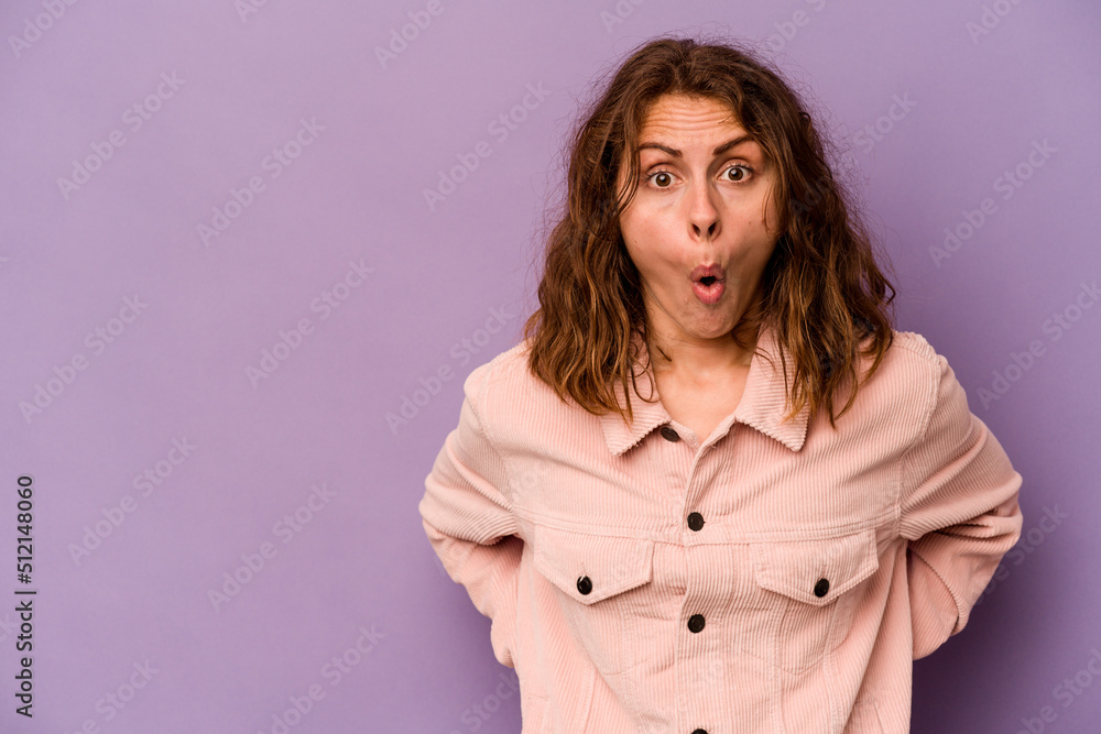 Young caucasian woman isolated on purple background being shocked because of something she has seen. Young caucasian woman isolated on purple background being shocked because of something she has seen.