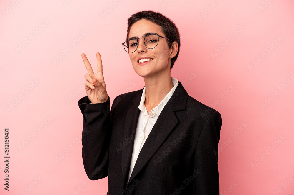 Young business woman isolated on pink background joyful and carefree showing a peace symbol with fingers. Young business woman isolated on pink background joyful and carefree showing a peace symbol with fingers.