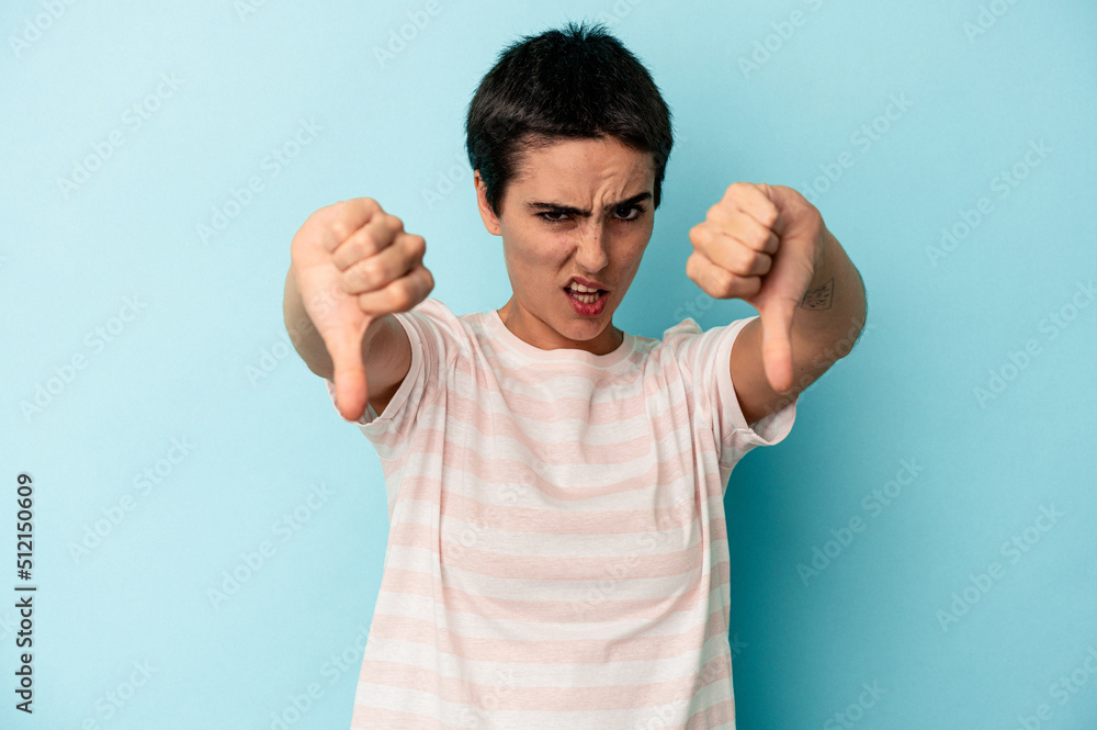 Young caucasian woman isolated on blue background showing thumb down and expressing dislike. Young caucasian woman isolated on blue background showing thumb down and expressing dislike.