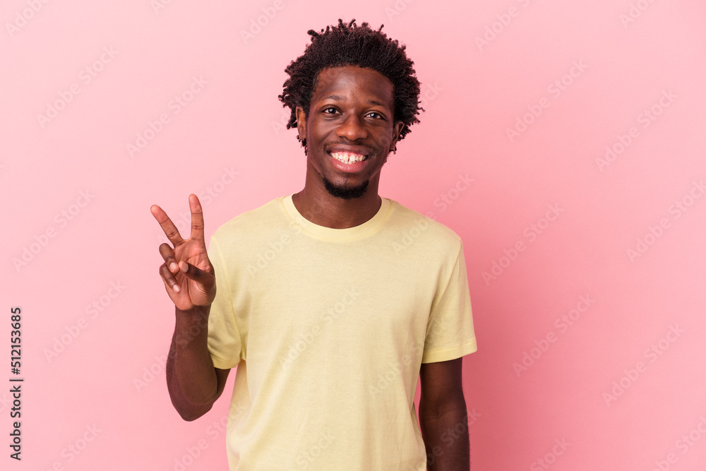 Young african american man isolated on pink background showing victory sign and smiling broadly. Young african american man isolated on pink background showing victory sign and smiling broadly.