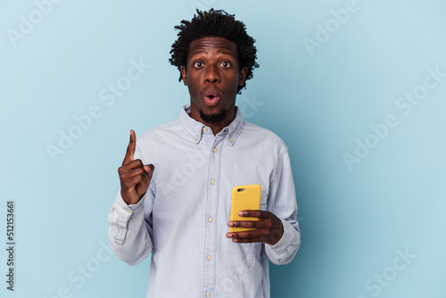 Young african american man holding mobile phone isolated on blue background having some great idea  concept of creativity.