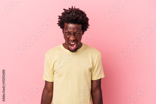 Young african american man isolated on pink background shouting very angry, rage concept, frustrated. © Asier