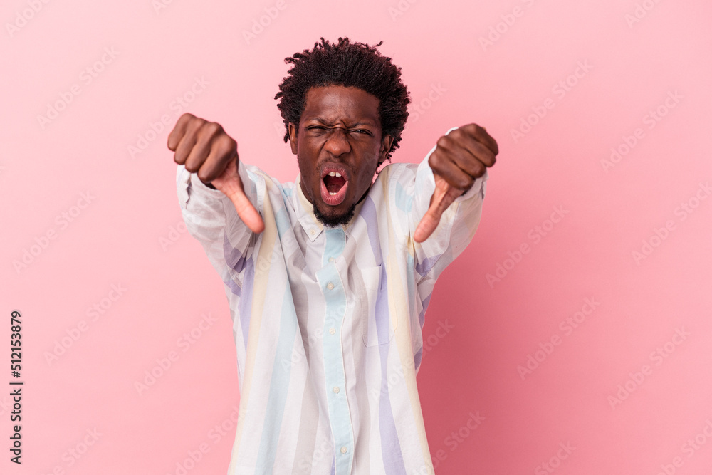 Young african american man isolated on pink background showing thumb down and expressing dislike. Young african american man isolated on pink background showing thumb down and expressing dislike.