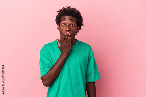 Young african american man isolated on pink background shocked, covering mouth with hands, anxious to discover something new. © Asier