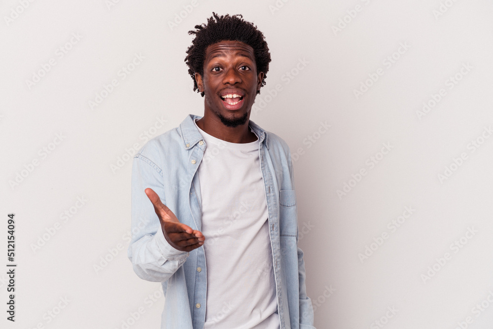 © Asier - Young african american man isolated on white background stretching hand at camera in greeting gesture. © Asier - Young african american man isolated on white background stretching hand at camera in greeting gesture.