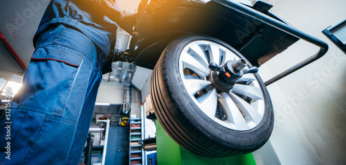 Obraz na płótnie Auto mechanic uses tire balancing machine and turning tire