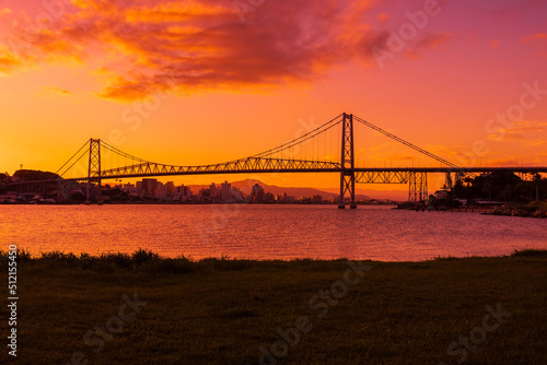 Hercilio luz cable bridge with bright sunset sky and reflection on water in Florianopolis