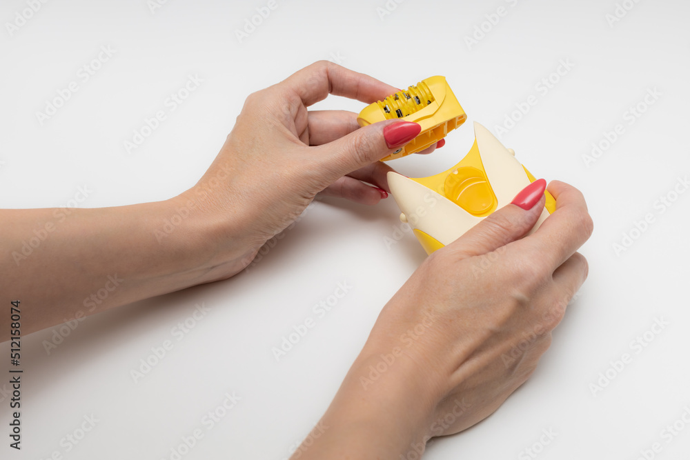 woman taking apart her epilator on a white background woman taking apart her epilator on a white background