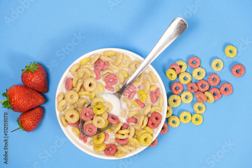 Quick breakfast cereal - rings with milk and strawberries on a blue background.
