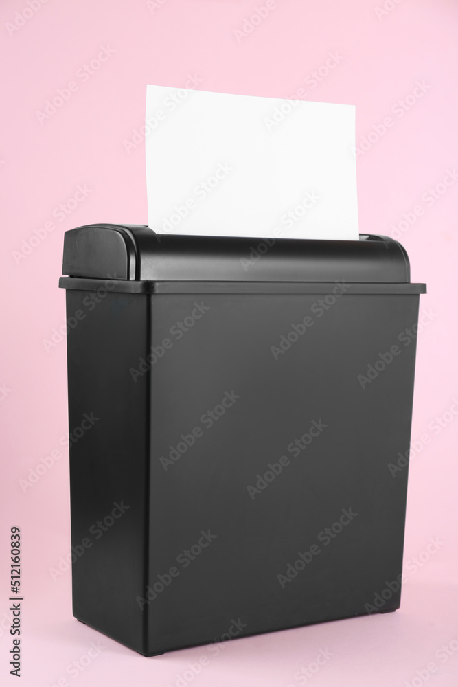 Shredder with sheet of paper on pink background Shredder with sheet of paper on pink background