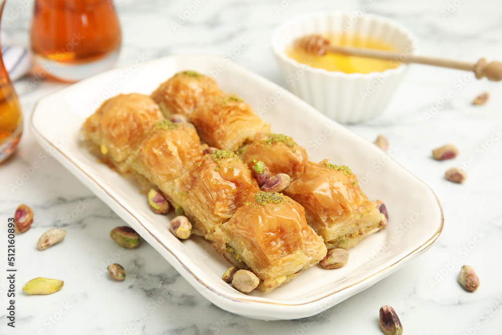 Delicious baklava with pistachios and scattered nuts on white marble table