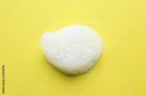 Drop of bath foam on yellow background, top view
