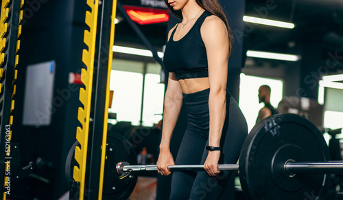 Attractive young sports woman doing barbell exercises. Crossfit and fitness. Beautiful young fitness woman exercising with heavy dumbbell in gym 