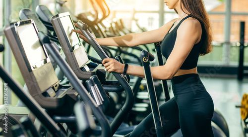 Portrait of fitness young woman in sports clothing exercising on cardio machine at gym