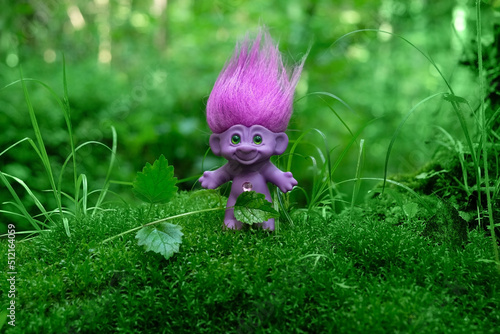 cute tale troll in forest  mossy natural green background. troll toy with ruffled violet hair in mystery forest  symbol of fairytale. magic atmosphere