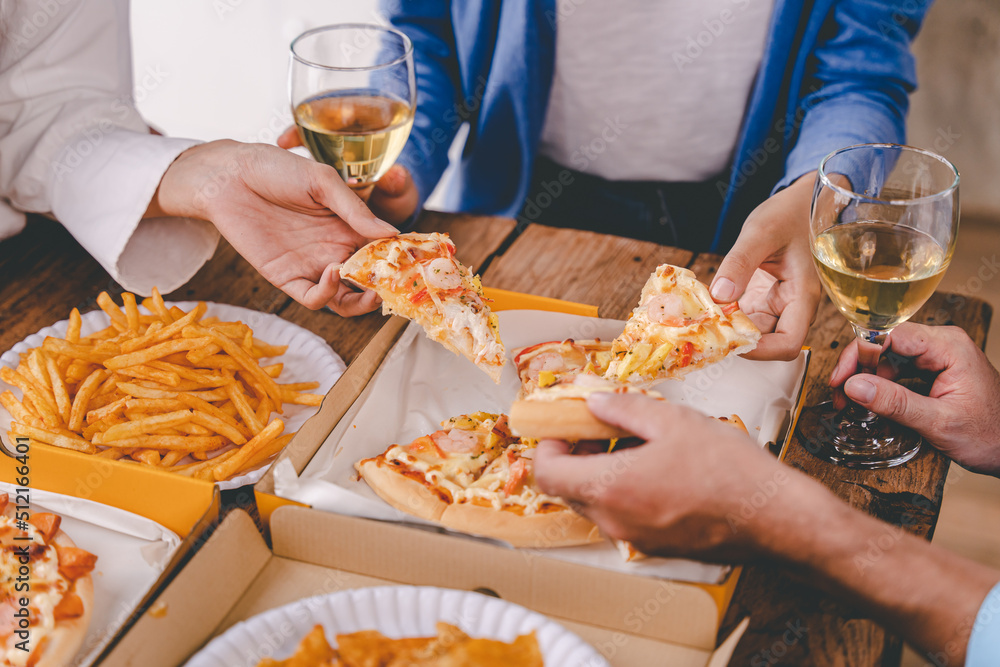 hands of a colleague or friend eating pizza After meeting at the office for a long time They're partying at home, eating pizza and having fun. food and drink people and holidays hands of a colleague or friend eating pizza After meeting at the office for a long time They're partying at home, eating pizza and having fun. food and drink people and holidays