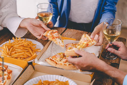 hands of a colleague or friend eating pizza After meeting at the office for a long time They're partying at home, eating pizza and having fun. food and drink people and holidays