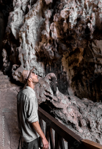 A young man wearing a hat is exploring a cave and having a look inside