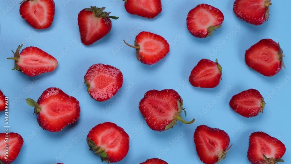 Rotating strawberry cut in half on a blue background, strawberry texture or trendy, summer fruit background Rotating strawberry cut in half on a blue background, strawberry texture or trendy, summer fruit background