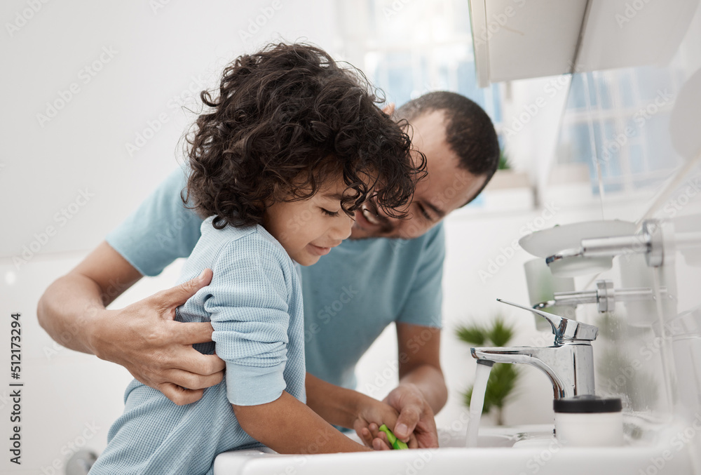 We brush now, and then later tonight again. Shot of a father helping his son rinse his toothbrush while brushing his teeth in the bathroom at home.