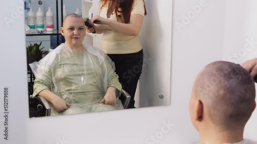 A woman in a barbershop shaved baldly shaves her head clean. Medium plan photo