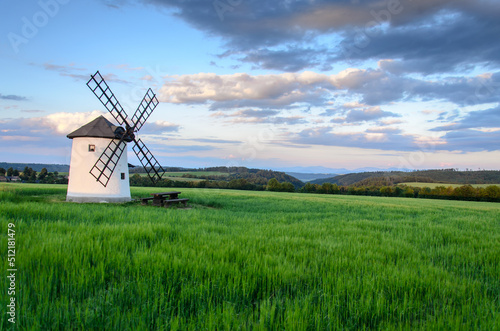 Obraz na płótnie Windmill in the middle of a field with mountain views in the early summer evening w salonie