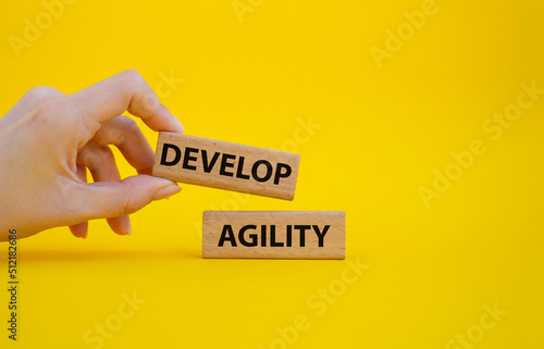 Develop agility symbol. Concept word Develop agility on wooden blocks. Beautiful yellow background. Businessman hand. Business and Develop agility concept. Copy space photo
