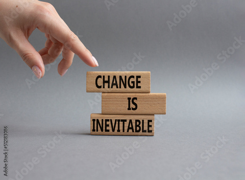 Change is Inevitable symbol. Wooden blocks with words Change is Inevitable. Beautiful grey background. Businessman hand. Business and Change is Inevitable concept. Copy space.