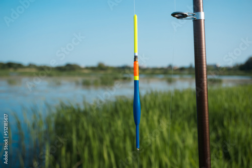 Float for fishing with a fishing rod, on the background of the lake.