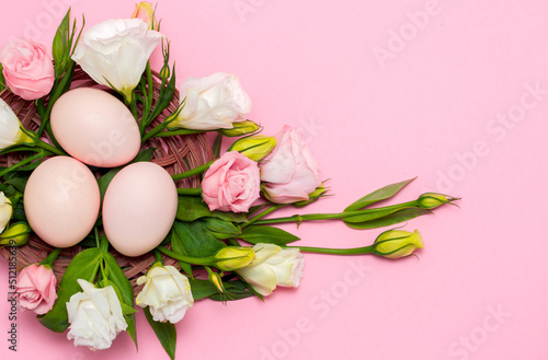 Easter background with Easter eggs and spring flowers. Top view with copy space. Nest with eggs decorated with beautiful flowers on a pink background. © Vera