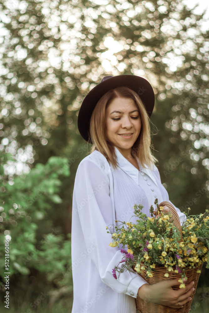 portrait of a happy girl with short hair in a black hat with a basket of flowers walking in a field portrait of a happy girl with short hair in a black hat with a basket of flowers walking in a field