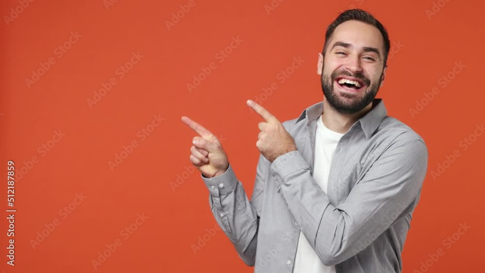 Promoter bright young brunet man 20s years old wears blue shirt pointing fingers hands aside on workspace copy space mockup promo commercial area isolated on plain orange background studio portrait Promoter bright young brunet man 20s years old wears blue shirt pointing fingers hands aside on workspace copy space mockup promo commercial area isolated on plain orange background studio portrait